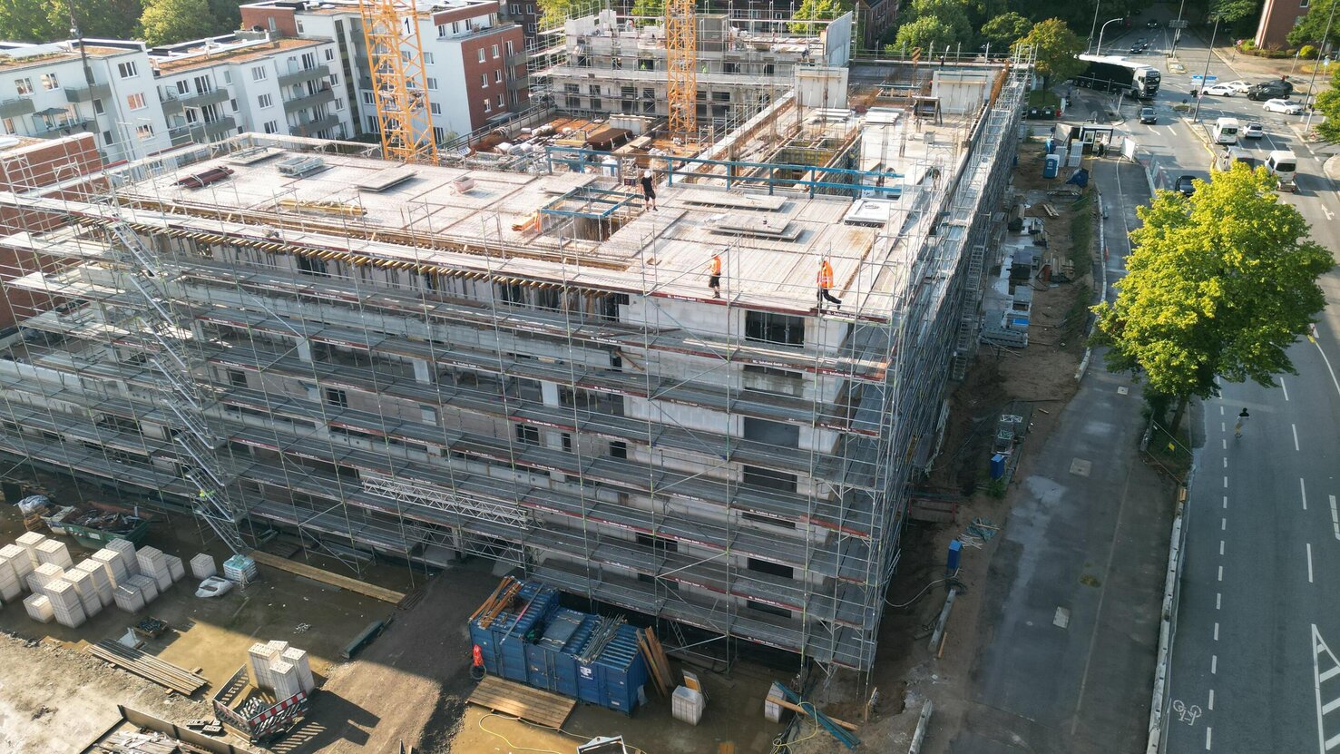 Luftaufnahme einer Baustelle mit einem gro&szlig;en Rohbau das komplett einger&uuml;stet ist