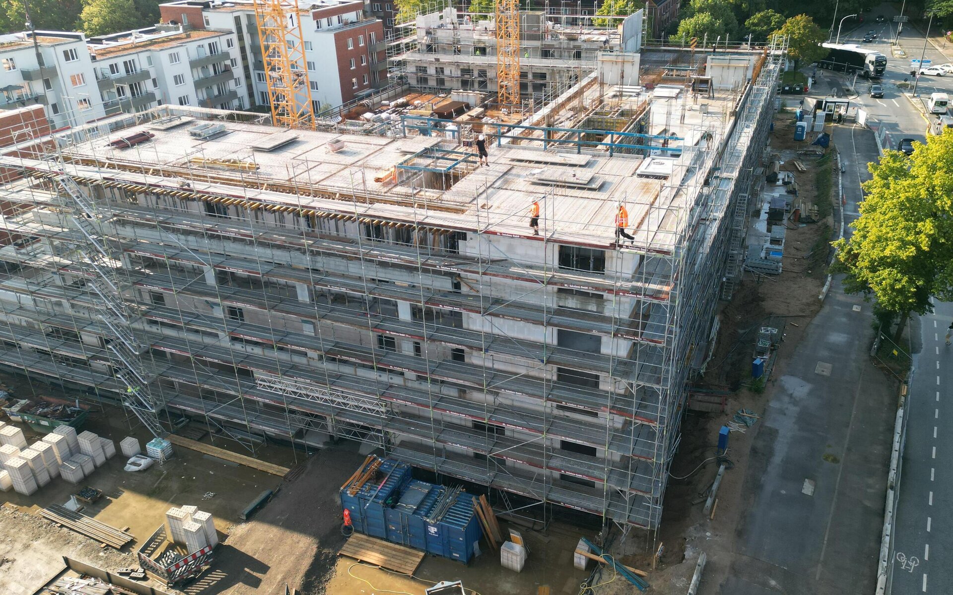 Luftaufnahme einer Baustelle mit einem gro&szlig;en Rohbau das komplett einger&uuml;stet ist