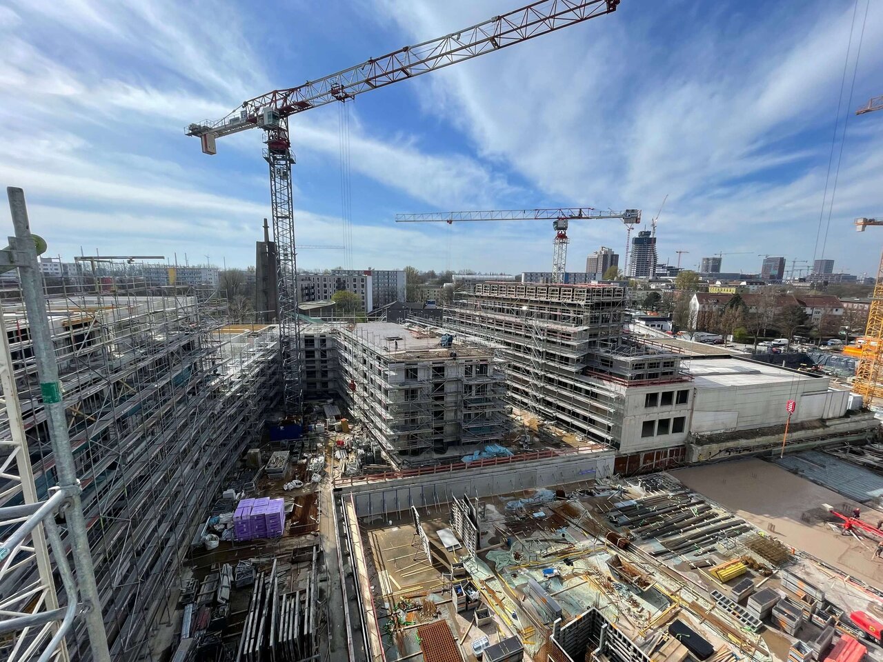 Gro&szlig;baustelle mit komplexem Systemger&uuml;st und Baukran vor blauem Himmel